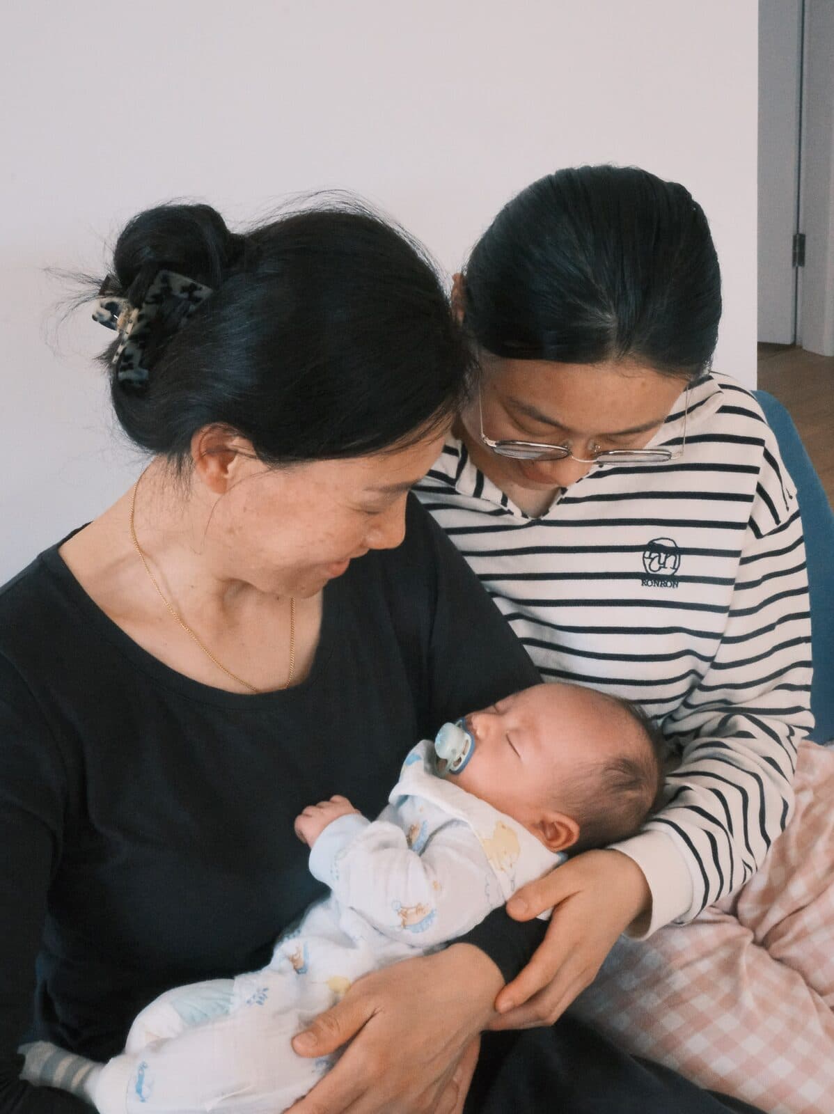 长辈与妈妈在自己家中一起照看新生儿