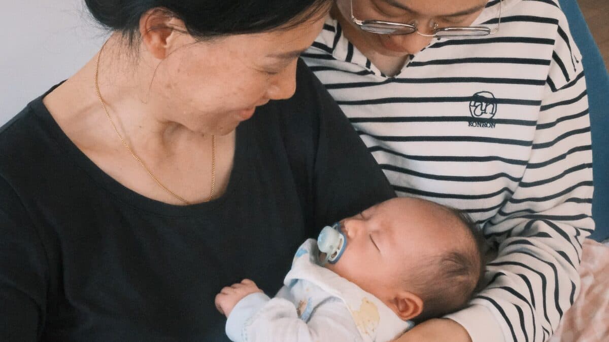 A carer with a sleeping newborn at home